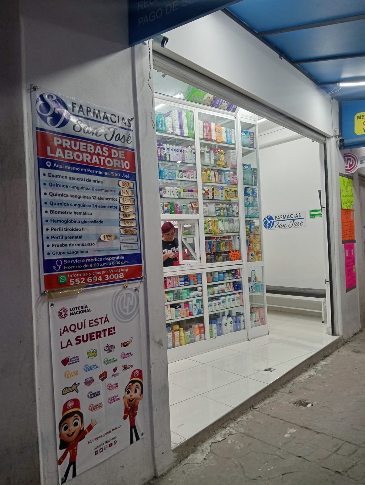 Pharmacy storefront with glass refrigerated display case stocked with medicines and products, signage advertising laboratory services