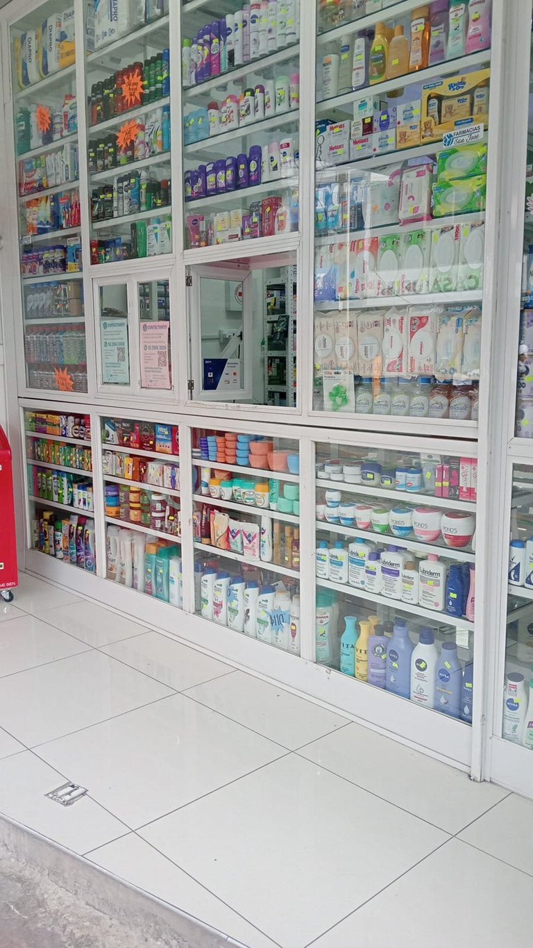 Pharmacy store shelving with glass doors displaying various medicines, toiletries, and health products organized by category
