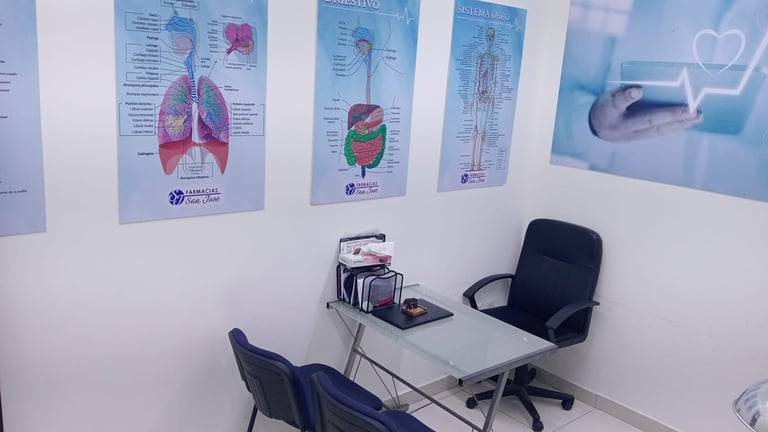 Medical office with anatomical posters on white wall, desk with computer monitor, stethoscope, and office chairs for patient consultation